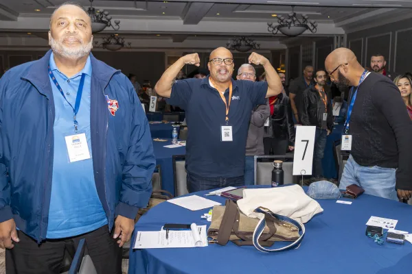 Three men stand around a table cheering.