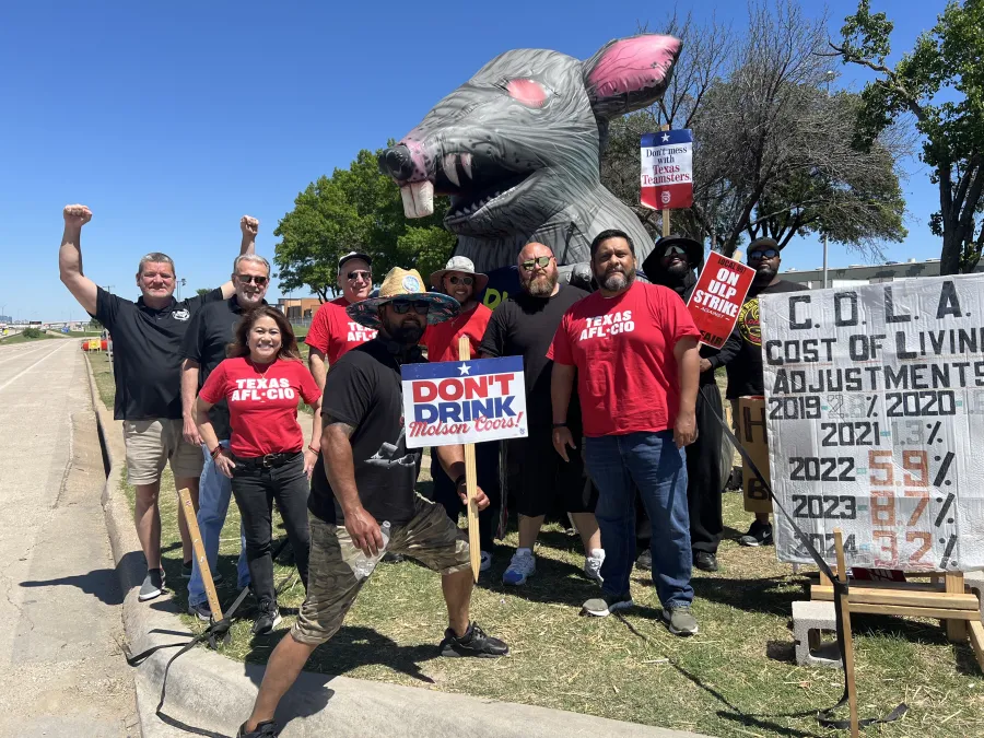 A group of union members poses in front of a Scabby the Rat figure in Forth Worth, Texas.