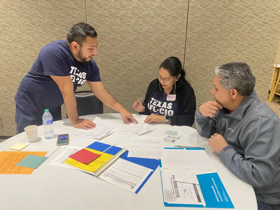 Two AFL-CIO staffers work with a Citizenship Clinic participant to fill out paperwork.